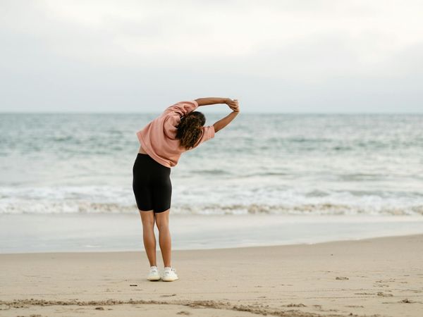 Person stretching outdoors at sunrise, feeling energized and free.